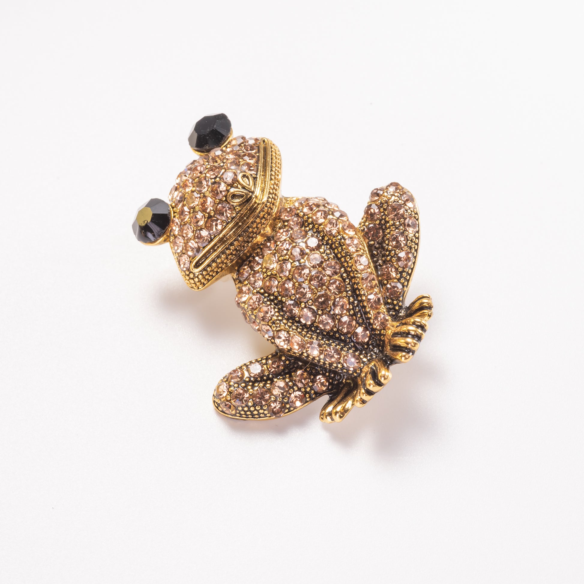 A yellow gold over brass brooch pin featuring a sparkling, champagne crystal-encrusted frog design.