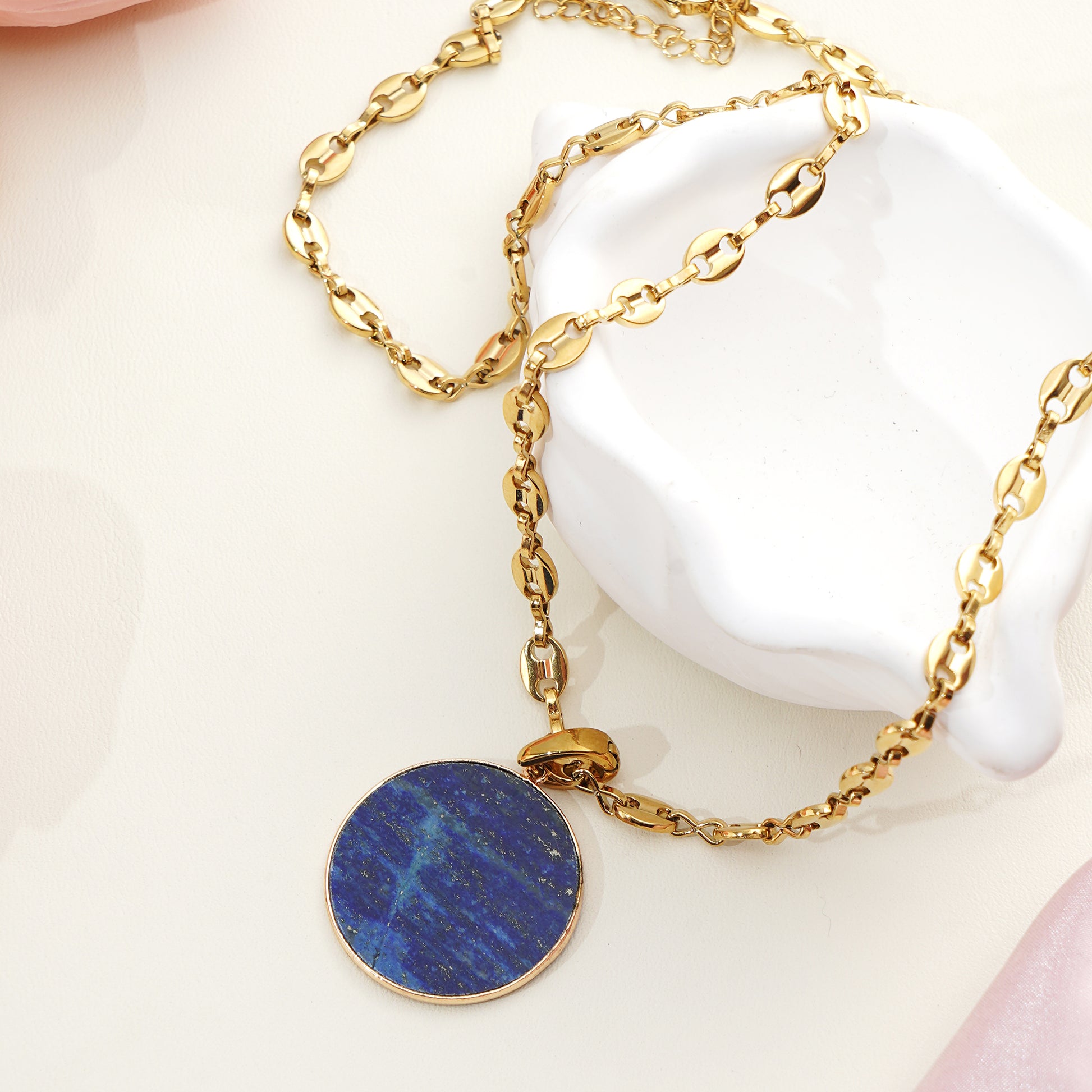 Blue necklace with a circular gemstone pendant on a white surface