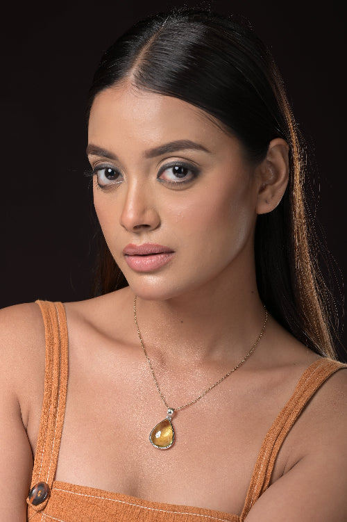 Woman wearing a necklace with a pendant against a dark background