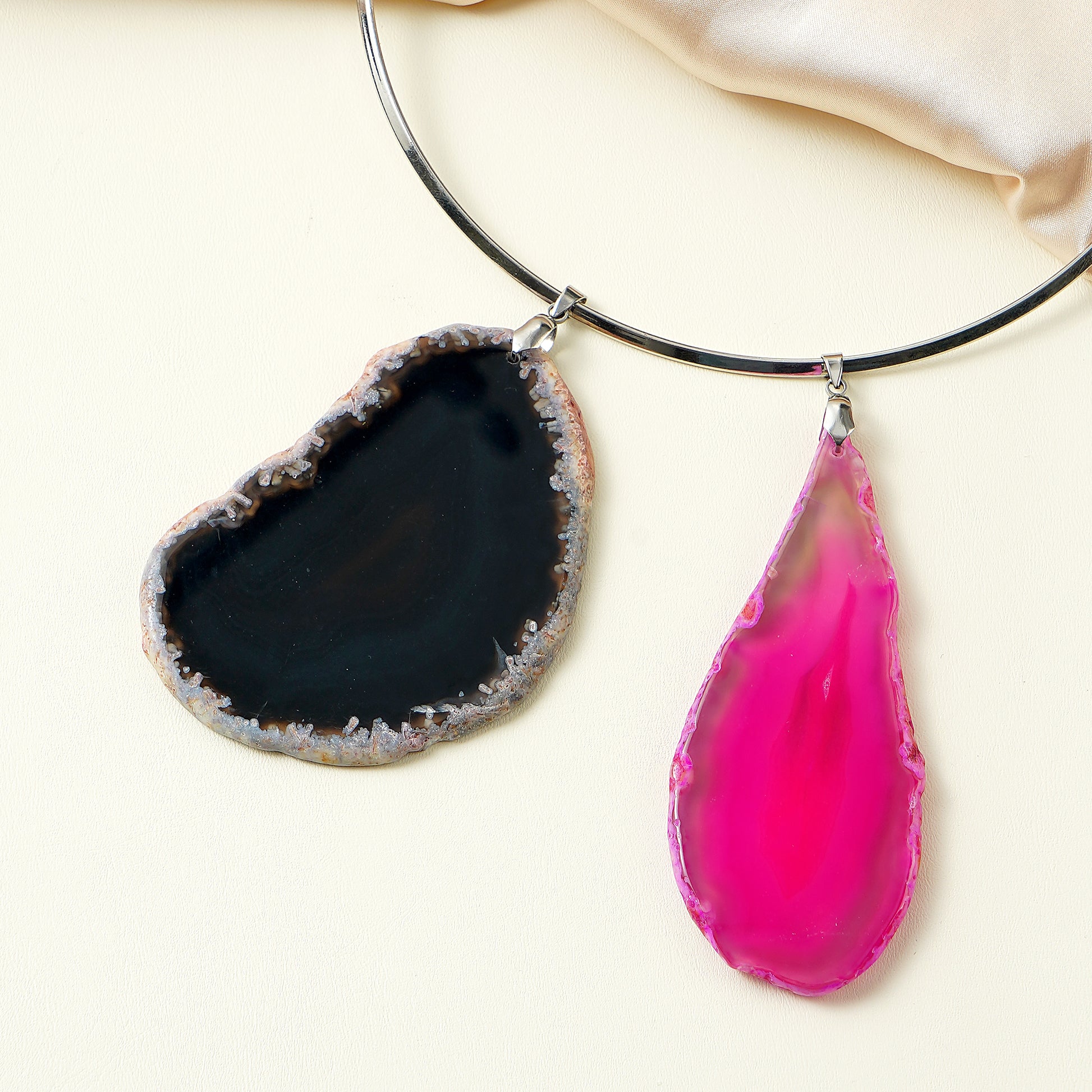 Necklace with two pendant stones, one black and one pink, on a light background.