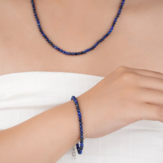 Person wearing a blue beaded bracelet and necklace on a white background