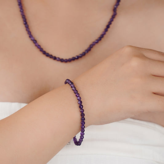 Person wearing a purple beaded bracelet and necklace 