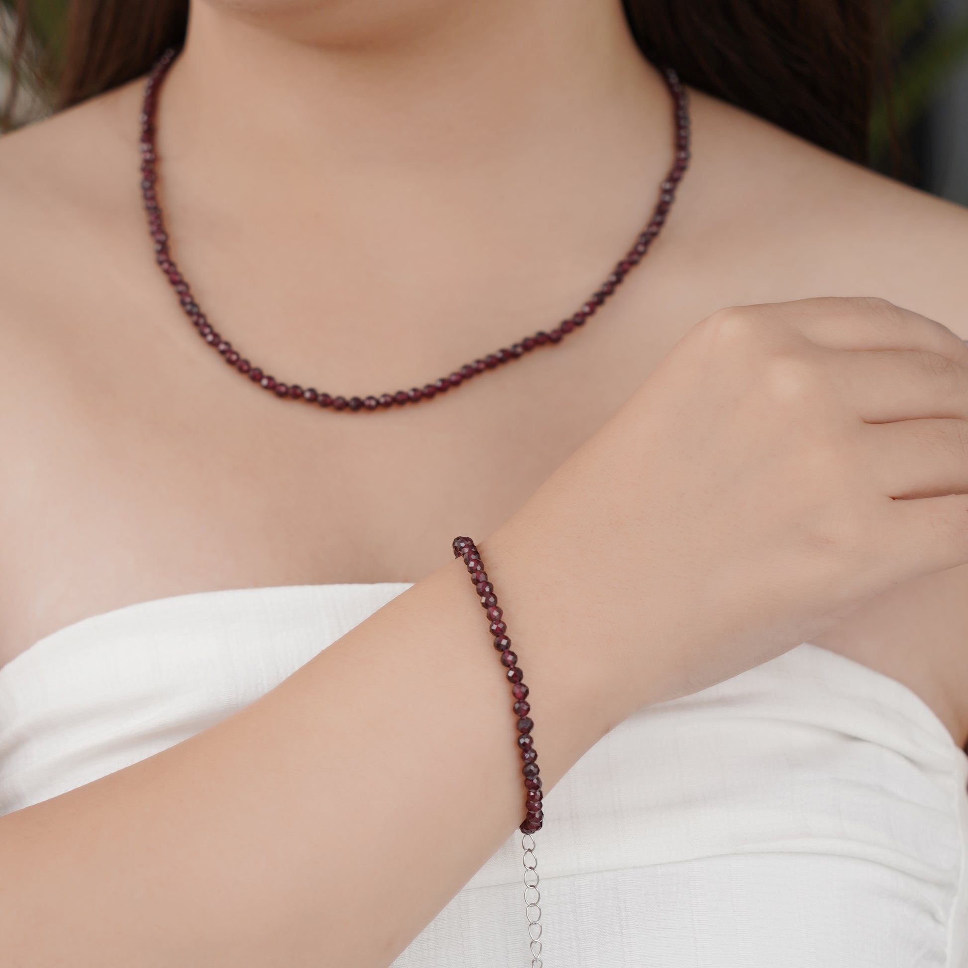 Person wearing a red beaded necklace and bracelet