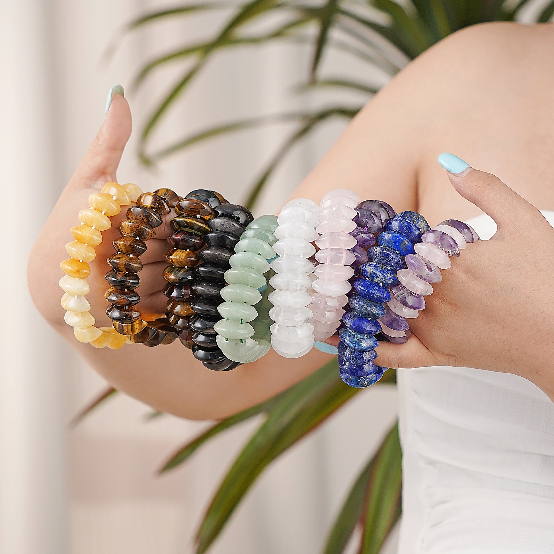 Set of colorful beaded bracelets on a person's wrist with a blurred plant background