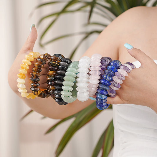 Set of colorful beaded bracelets on a person's wrist with a blurred plant background