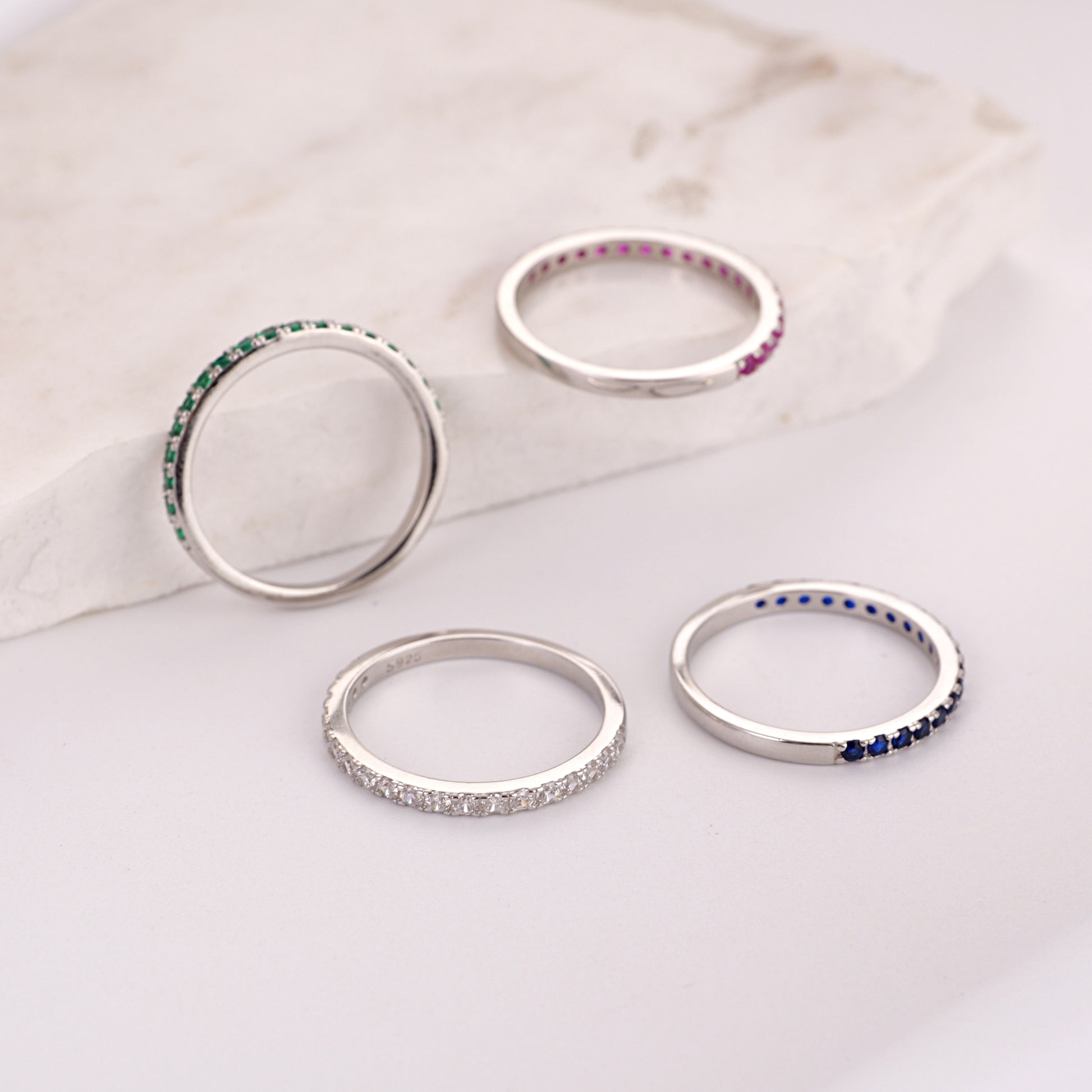 Set of silver rings with gemstone accents on a light background