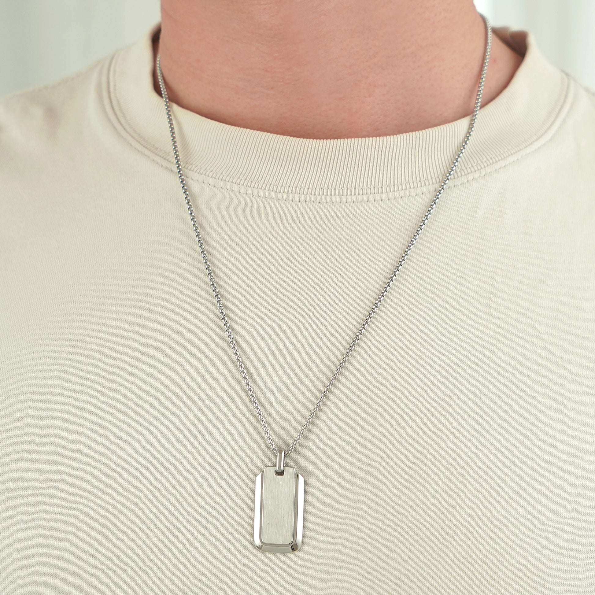 Silver necklace with a rectangular pendant worn by a person