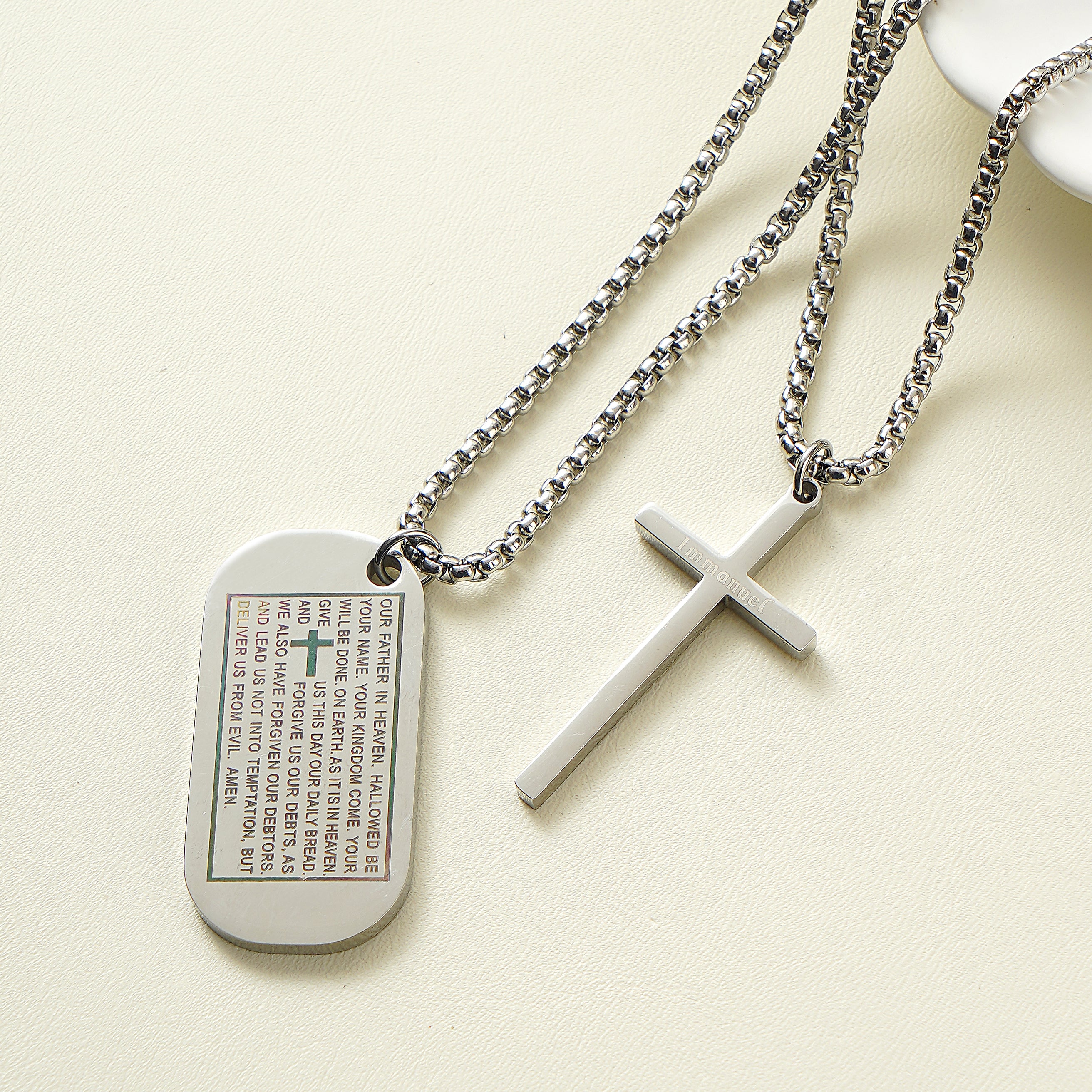 Stainless steel dog tag necklace engraved with the Lord's Prayer and a separate cross overlay.