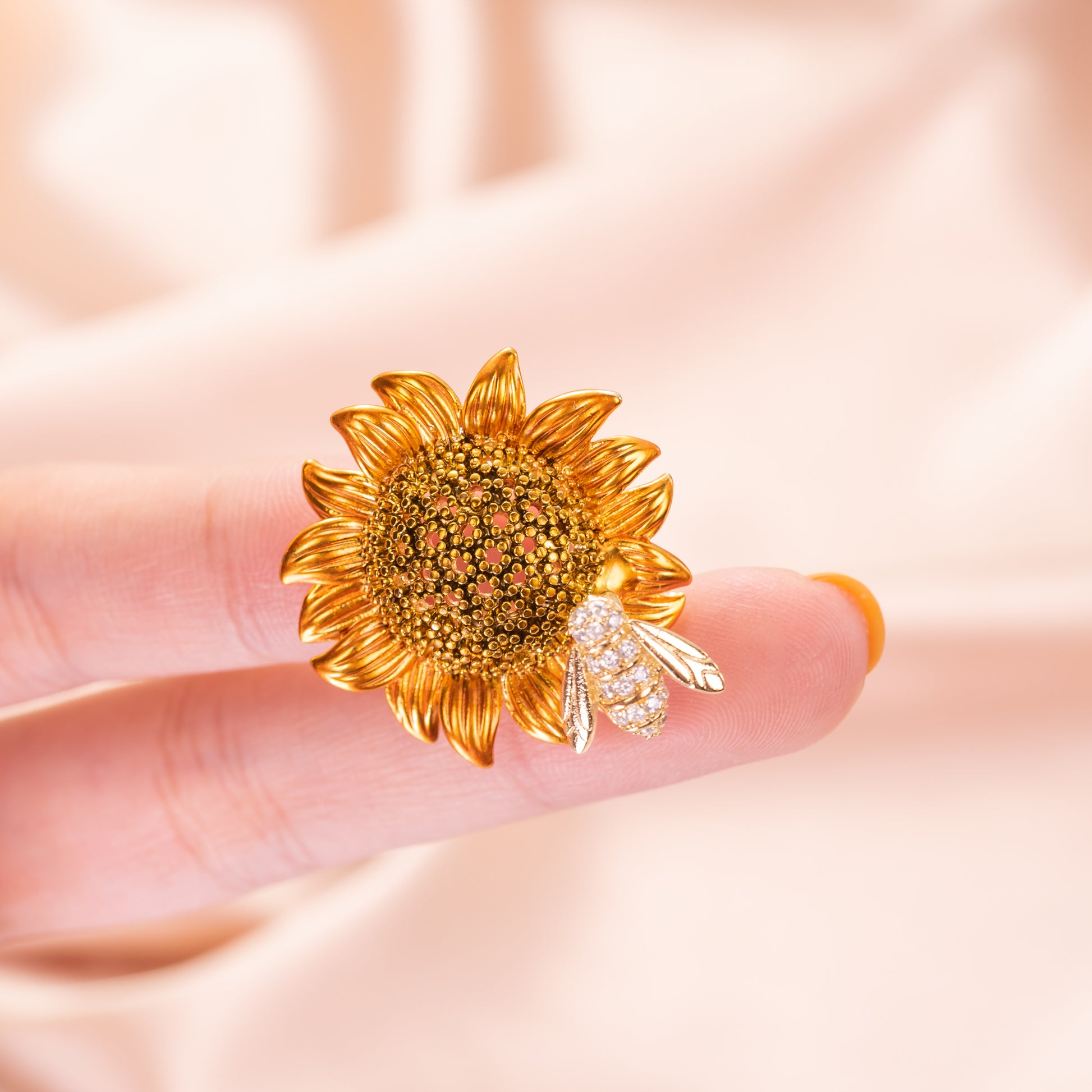 A brooch pin featuring a sunflower with a bee on top, made with cubic zirconia.