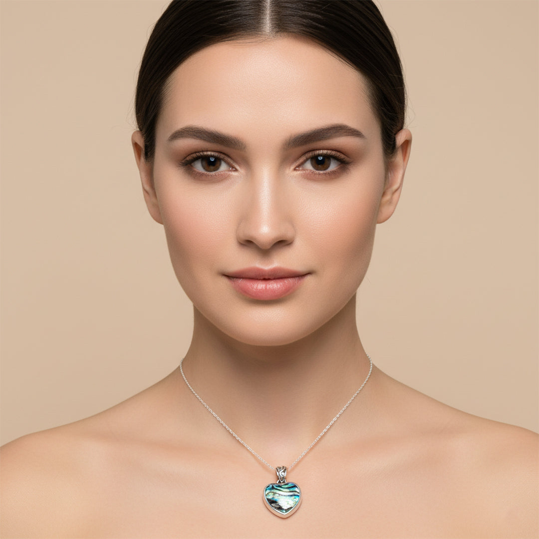 Woman wearing a necklace with a heart-shaped pendant against a beige background