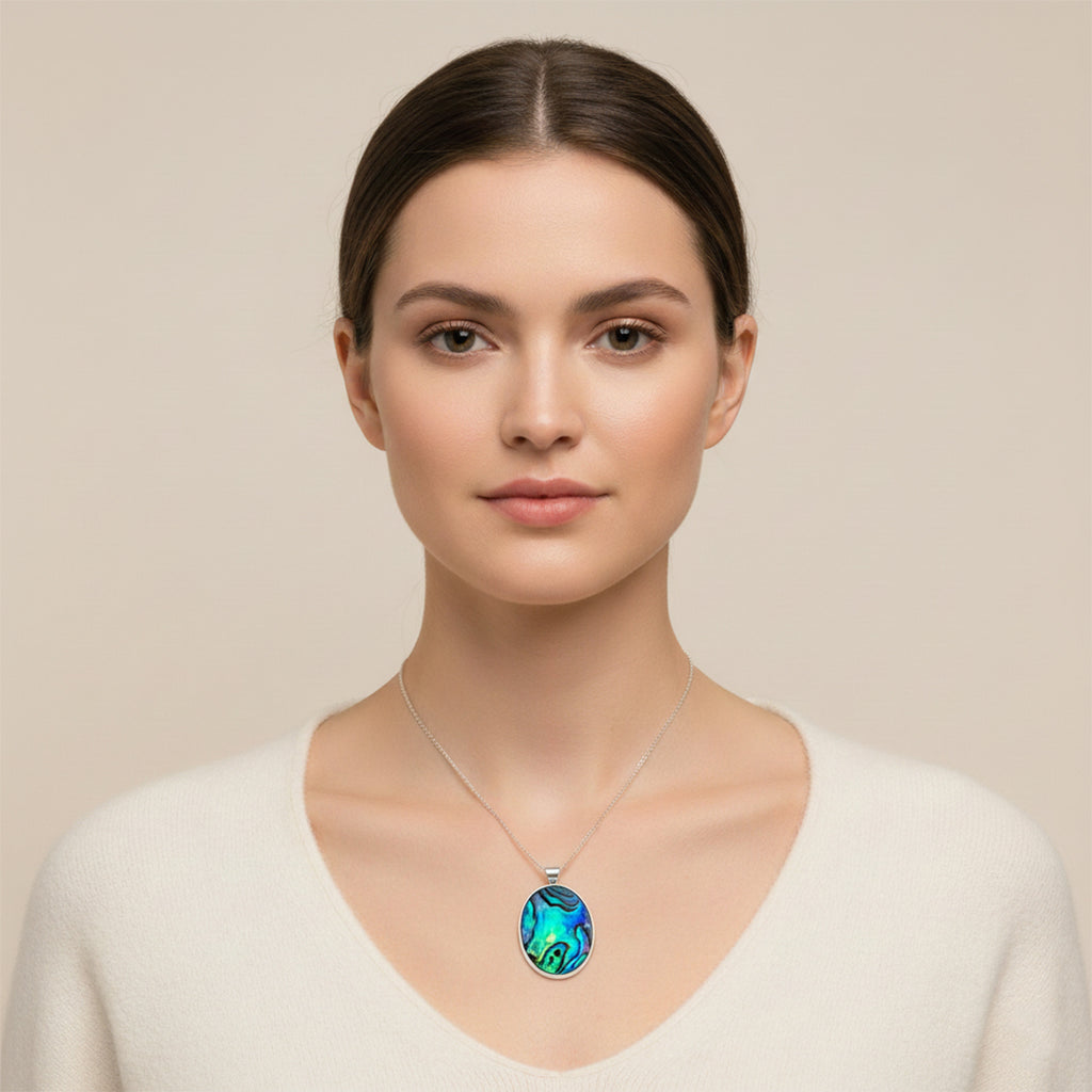 Woman wearing a necklace with an oval pendant on a beige background