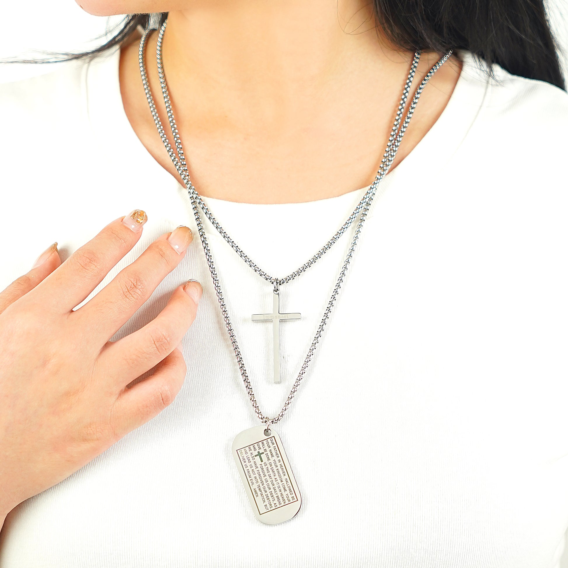 Woman wearing religious dog tag jewelry with engraved scripture and cross charm.