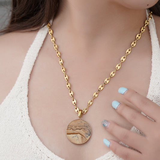 Gold necklace with a gemstone pendant worn by a person, focusing on the jewelry.