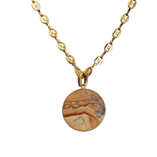 Gold necklace with a round gemstone pendant on a white background