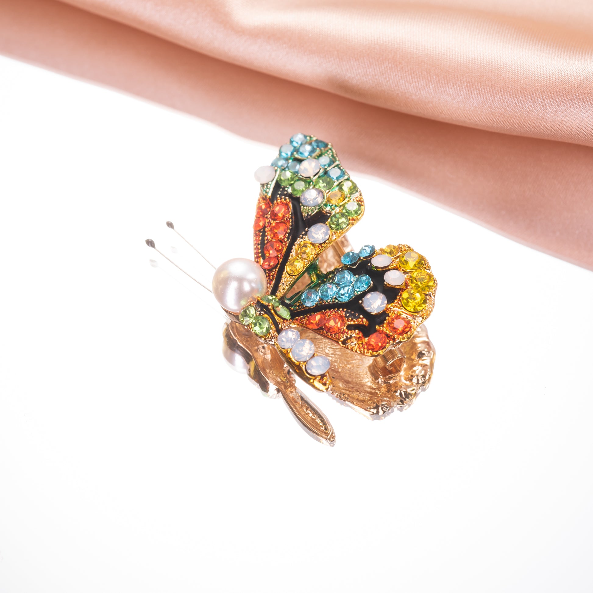 Colorful butterfly-shaped brooch with gemstones on a white background