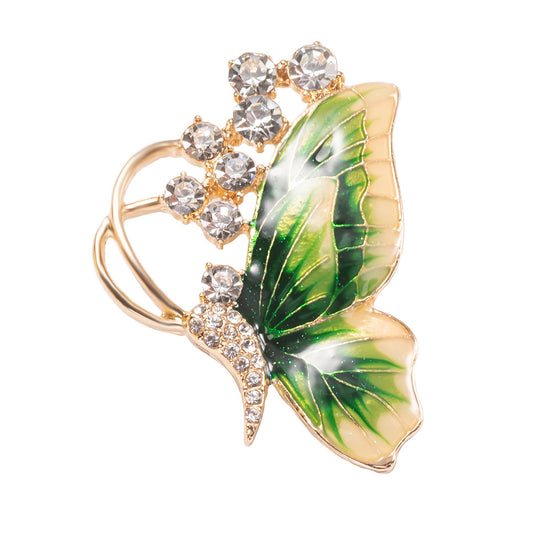 Butterfly-shaped brooch with green wings and crystal accents on a white background