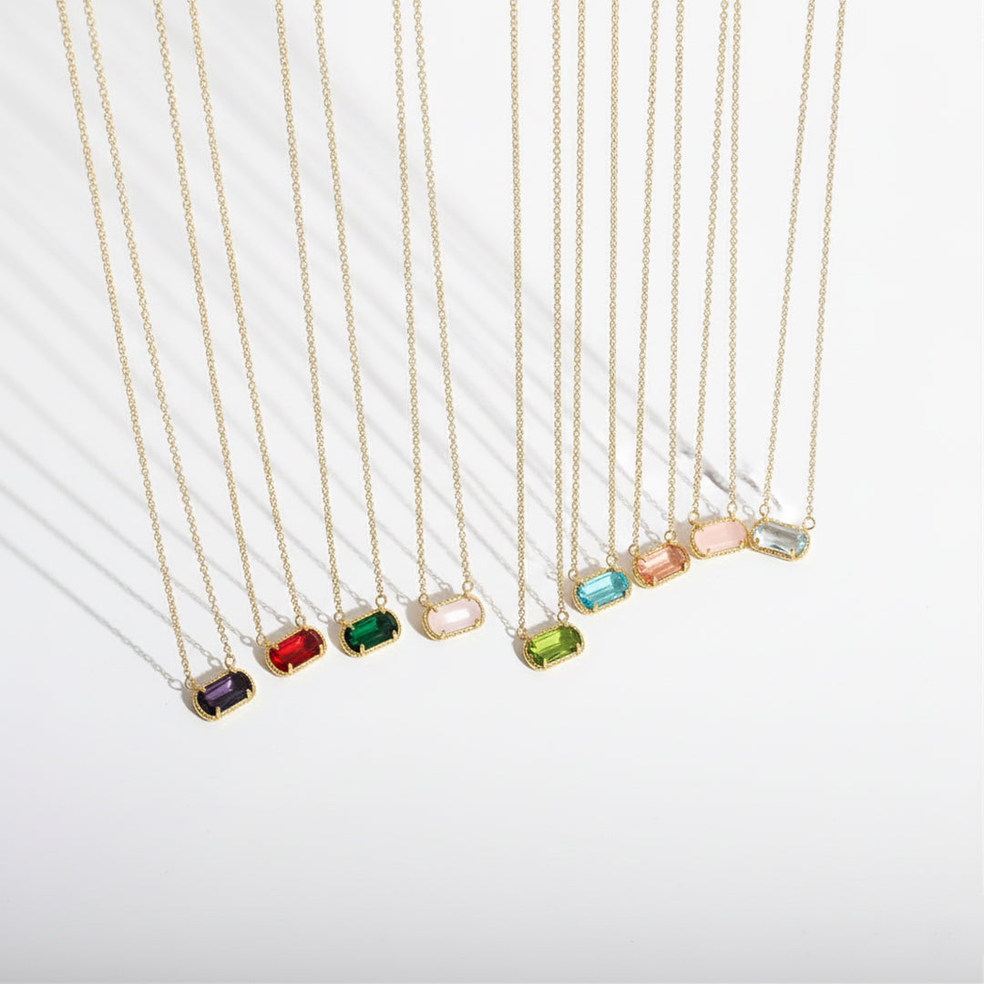 Set of gold necklaces with colorful gemstones on a white background