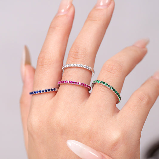 Hand wearing multiple rings with colored stones 