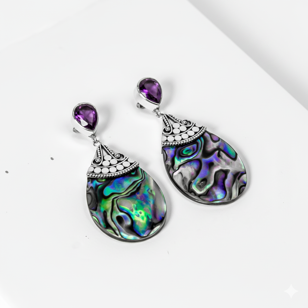 Teardrop-shaped earrings with colorful paua shell and purple gemstones on a white background