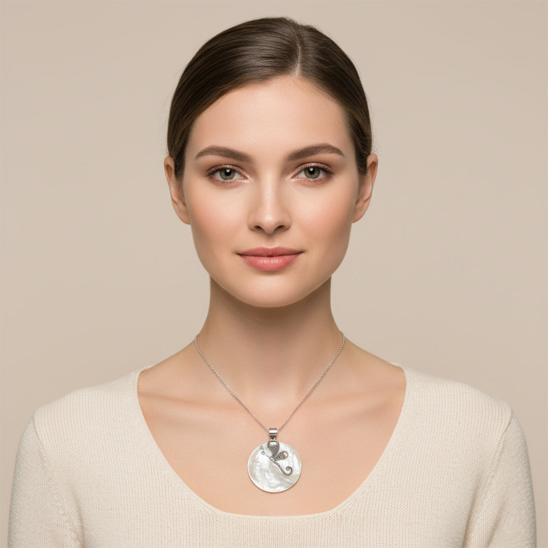 Woman wearing a silver necklace with a pendant against a beige background