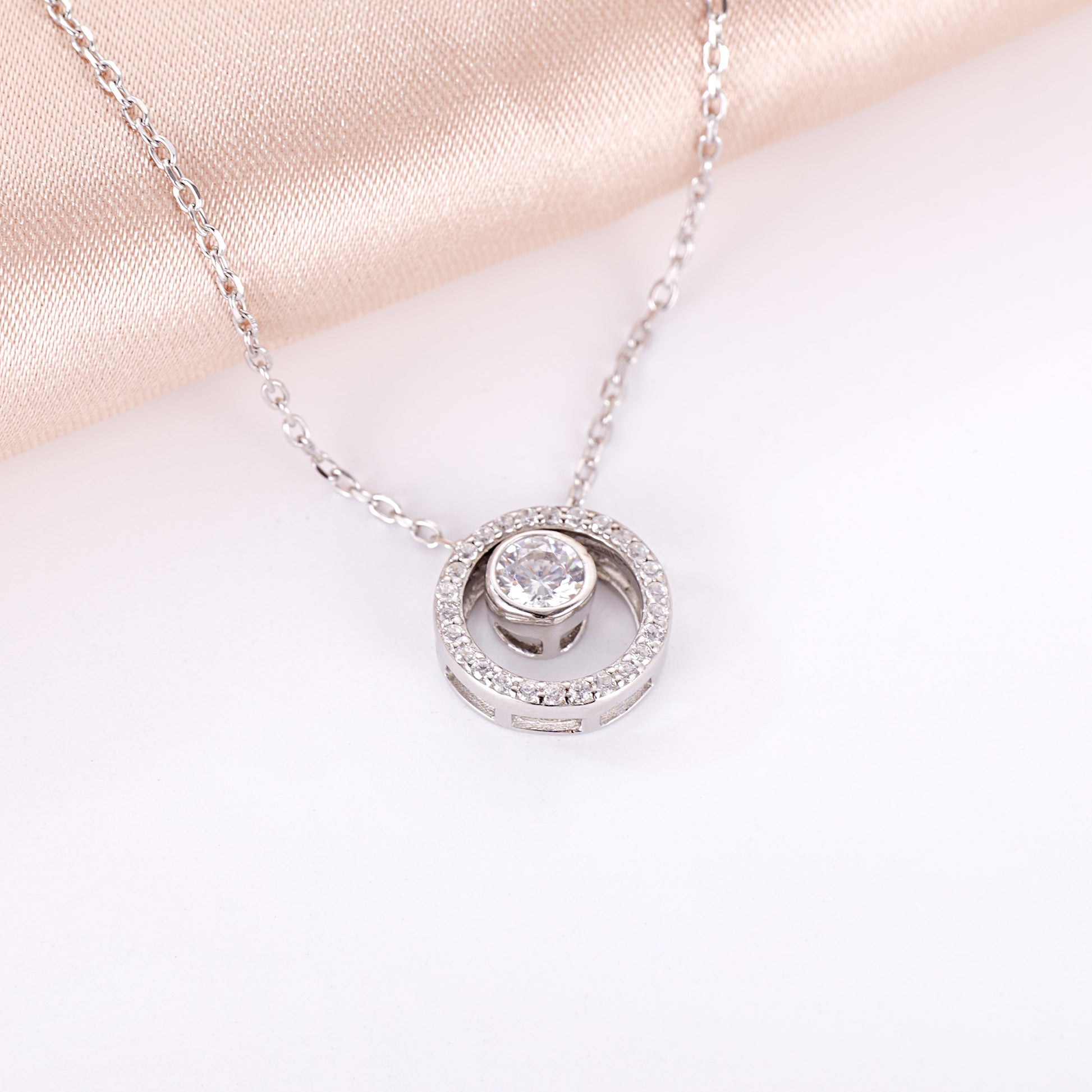 the brilliant round cubic zirconia framed by a polished silver circle pendant.