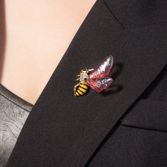 the glossy pink enamel body and textured metal wings on a bee lapel pin